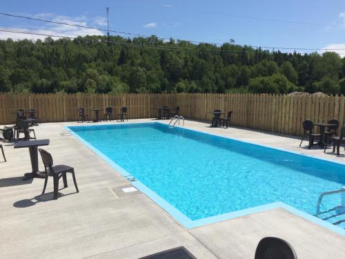 a swimming pool with tables and chairs next to a fence at Centre de Vacances 5 Étoiles Family Resort in Sacré-Coeur-Saguenay