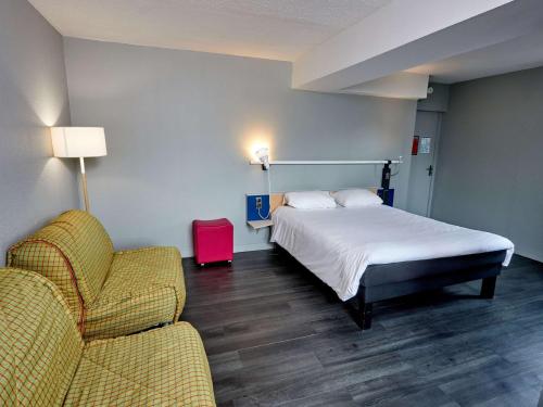 a bedroom with a bed and a couch and a chair at ibis Auxerre Sud in Venoy