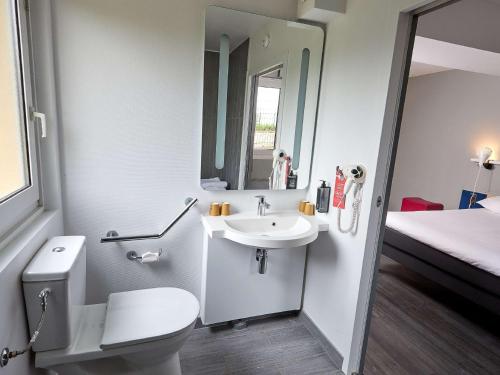 łazienka z toaletą, umywalką i łóżkiem w obiekcie ibis Auxerre Sud w mieście Venoy