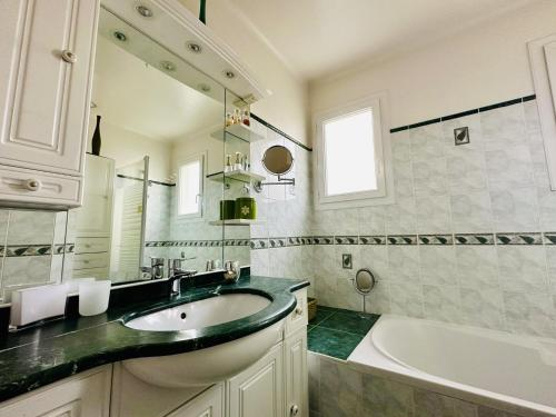 une salle de bain avec un lavabo et une baignoire dans l'établissement Maison de famille au calme quartier de la Marcelliere, à Les Sables-dʼOlonne