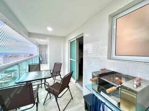 Cette chambre dispose d'un balcon avec une table et des chaises. dans l'établissement AP alto padrão no Caiçara, à Praia Grande