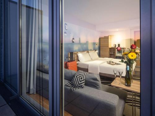 ein Hotelzimmer mit einem Bett und einem Sofa und einem Zimmer in der Unterkunft Novotel Wien City in Wien