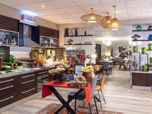 - une cuisine avec une table et des chaises dans un restaurant dans l'établissement Mercure Hotel Forbach Centre de Loisirs, à Forbach