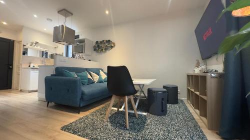 un salon avec un canapé bleu et une table dans l'établissement By nuit-parisienne Villemomble joli appartement tout confort, à Villemomble
