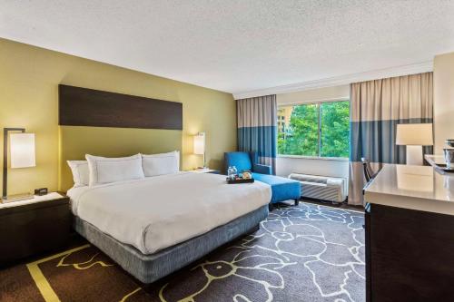 a hotel room with a large bed and a blue chair at Doubletree by Hilton Charlotte Uptown in Charlotte