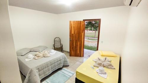 a bedroom with a bed and a table and a door at Casa Flor da Serra in Nobres