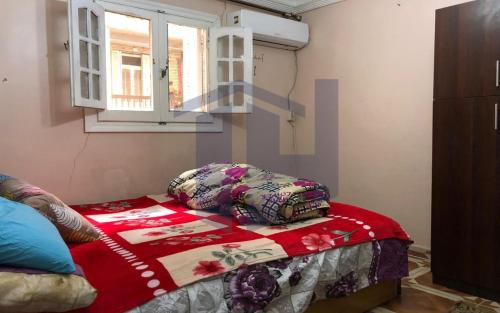 a bedroom with a bed with a red blanket and a window at BLUE Wave in Alexandria