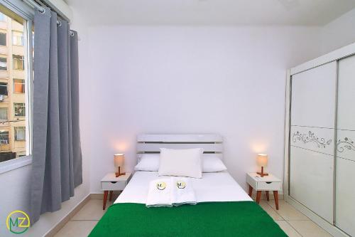 1 dormitorio con 1 cama con manta verde en Ótimo 2 quartos na quadra da praia para 6 pessoas, en Río de Janeiro