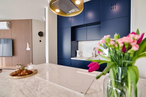 a kitchen with blue cabinets and a vase of pink flowers at Apartamenty Laguna Beskidów - A15 in Zarzecze