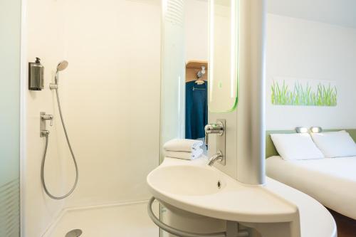 a white bathroom with a shower and a sink at ibis budget Brugge Centrum Station in Bruges