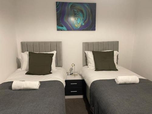 Jdb Romford Apt - Cosy 2 Bedroom with parking في Harold Wood: سريرين يجلسون بجانب بعض في غرفة النوم