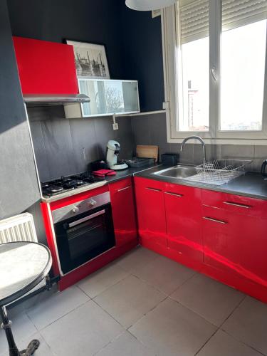 une petite cuisine avec des armoires rouges et un évier dans l'établissement Appartement Sympas à Puteaux, à Puteaux