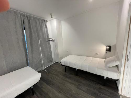 Cette chambre blanche comprend deux lits et une lampe. dans l'établissement HI Parque das Nações – Pousada de Juventude, à Lisbonne