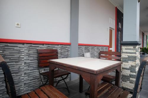 uma mesa e cadeiras num quarto com uma parede de tijolos em RedDoorz at Jalan Dieng 3 em Wonosobo