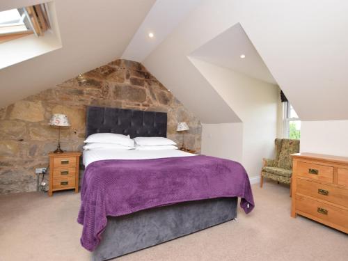 2 Bed in Edinburgh 83967 في روزلين: غرفة نوم بسرير كبير وجدار حجري