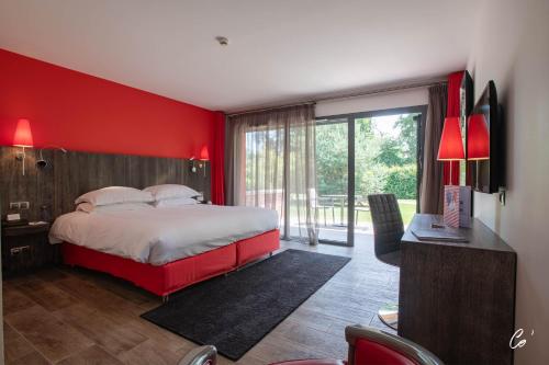 1 dormitorio con pared roja, cama y escritorio en Hôtel du Bois Blanc Domaine d'Epeyssoles Georges Blanc en Vonnas