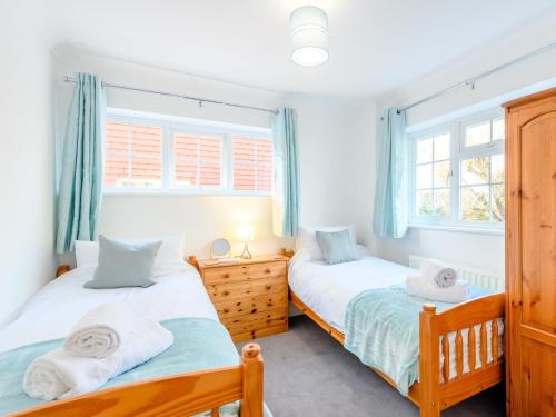 two beds in a room with two windows at 4 Bed in Brockenhurst 80420 in Brockenhurst