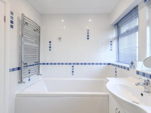 Baño blanco con bañera y lavamanos en 4 Bed in Brockenhurst 80420 en Brockenhurst