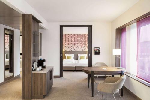 a living room with a table and a bedroom at Vienna House by Wyndham zur Bleiche Schaffhausen in Schaffhausen