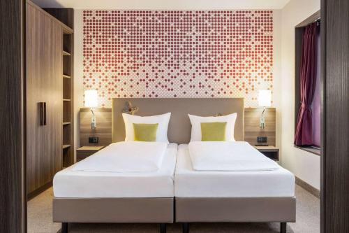 a bedroom with a large white bed with two pillows at Vienna House by Wyndham zur Bleiche Schaffhausen in Schaffhausen