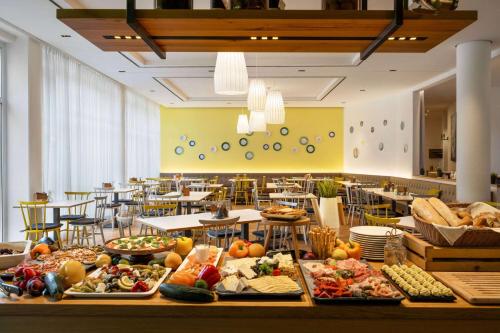 a buffet line of food in a restaurant with tables at Vienna House Easy by Wyndham Landsberg in Landsberg am Lech