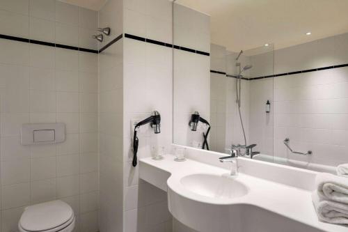 a white bathroom with a sink and a toilet at Vienna House Easy by Wyndham Landsberg in Landsberg am Lech