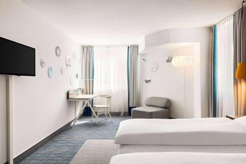 a hotel room with two beds and a desk at Vienna House Easy by Wyndham Limburg in Limburg an der Lahn