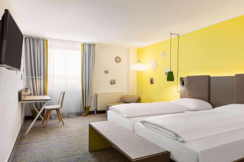 a hotel room with two beds and a desk at Vienna House Easy by Wyndham Limburg in Limburg an der Lahn