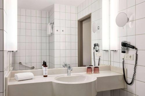 a bathroom with a sink and a mirror at Vienna House Easy by Wyndham Limburg in Limburg an der Lahn