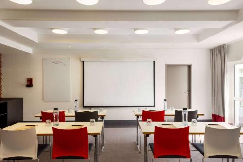 a classroom with tables and chairs and a whiteboard at Vienna House Easy by Wyndham Limburg in Limburg an der Lahn