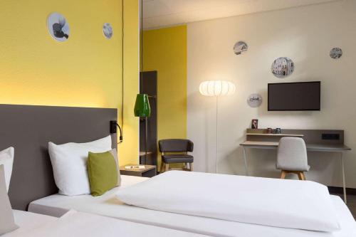 1 dormitorio con 1 cama, 2 sillas y TV en Vienna House Easy by Wyndham Amberg, en Amberg