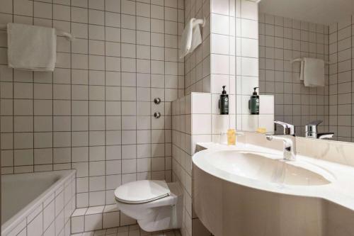 a white bathroom with a sink and a toilet at Vienna House Easy by Wyndham Amberg in Amberg