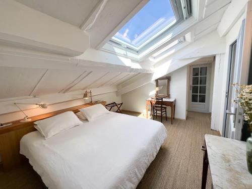 - une chambre avec un grand lit blanc et une lucarne dans l'établissement Casaviel, à Biarritz