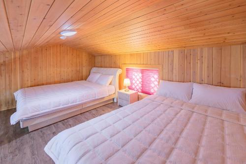 a bedroom with two beds in a wooden room at Suncheonbay Reed Field Pension in Suncheon