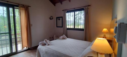 1 dormitorio con 1 cama blanca y 2 ventanas en A´mar en Villa General Belgrano