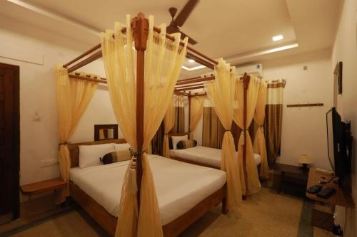 a bedroom with two beds with curtains and a tv at ROYAL STAY VINTAGE in Madurai