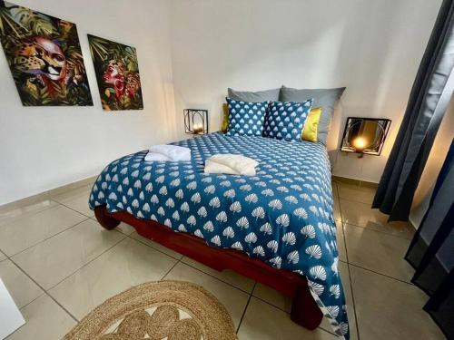 a bedroom with a bed with a blue and white comforter at La villa Loca Reunion in Saint-Joseph