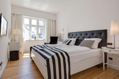 Schlafzimmer mit einem großen weißen Bett mit einem schwarzen Kopfteil in der Unterkunft Die Schlosserei in Westerland