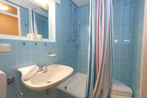 een blauwe badkamer met een wastafel en een douche bij Haus am Meer14 - App. 048a WB in Westerland