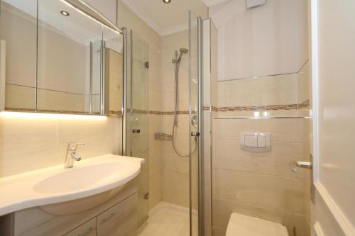 ein weißes Bad mit einem Waschbecken und einer Dusche in der Unterkunft Horstmann 17 O in Westerland