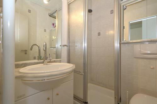 uma casa de banho branca com um lavatório e um chuveiro em Dorow 48 WB em Westerland