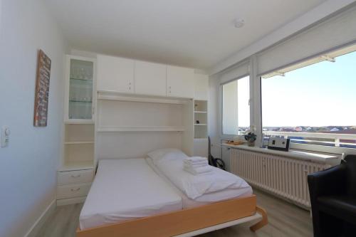 ein kleines Schlafzimmer mit einem Bett und einem großen Fenster in der Unterkunft Dorow 48 WB in Westerland