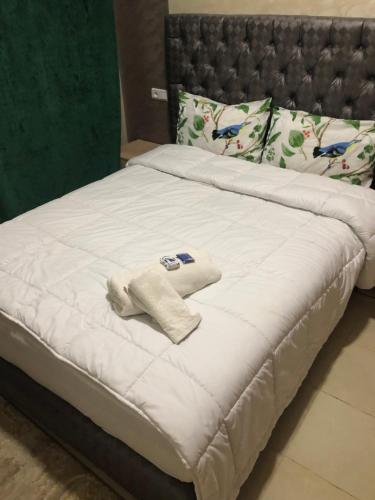 a bed with a white blanket and pillows on it at Hotel Tidinit in Guelmim