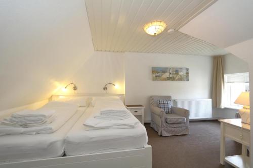 - une chambre avec deux lits blancs et une chaise dans l'établissement Friesenhaus App. I, à Westerland