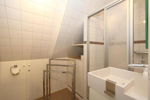 La salle de bains blanche est pourvue d'un lavabo et d'une douche. dans l'établissement Friesenhaus App. I, à Westerland