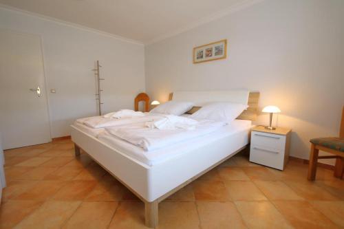 a large white bed in a room with a table at App. Hackmack 62 in Westerland
