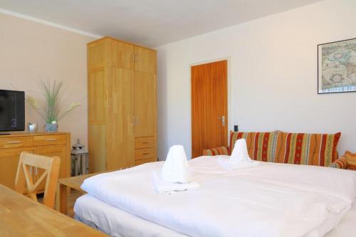 a bedroom with a white bed and a wooden cabinet at App. Heckermann in Wenningstedt
