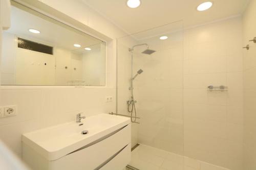 a white bathroom with a sink and a shower at Haus Metropol, App. 109 in Westerland (Sylt)