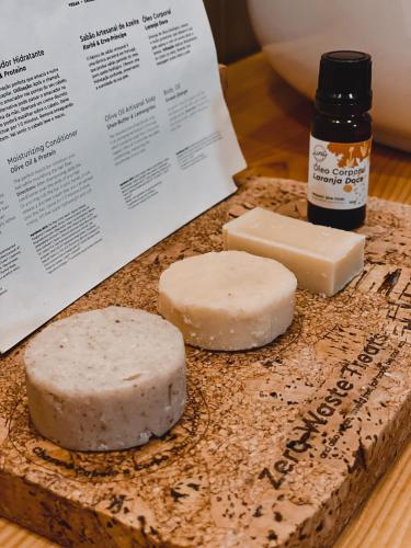 two slices of cheese on a cutting board with a bottle of essential oils at Craveiral Farmhouse by Belong Staying & Feeling in São Teotónio