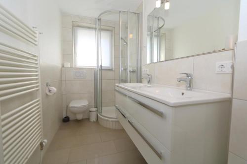 a white bathroom with a sink and a toilet at App König 01 in Westerland (Sylt)